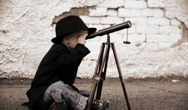 Criança olhando por uma luneta